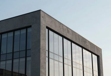A sleek, minimalist North American / US office building exterior reflecting a clear sky, highlighting clean lines and a professional Slate Grey palette.