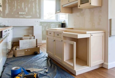 Professional kitchen renovation featuring new wood cabinets, power tools, and white subway tile backsplash installation.
