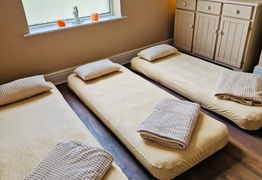 Three air beds on the floor with blankets and pillows
