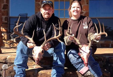 Brent and Vanya Keyser, owners of Loyal Valley Outfitters, posing with trophy deer mounts at their Mason County Texas ranch.