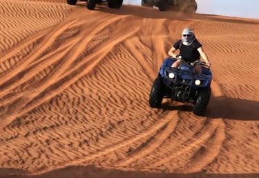 Tourist riding a quad bike on Dubai desert sand dunes during a desert safari