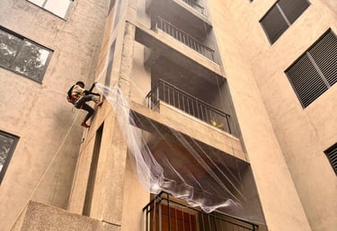 Technician carefully installing a balcony safety net in a high-rise Bangalore apartment.