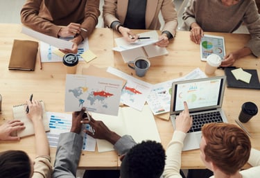Diverse business team reviewing financial data charts and analytics on laptop during meeting.