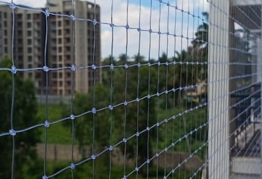 A technician carefully installing a sturdy safety net on a residential balcony in Chennai.