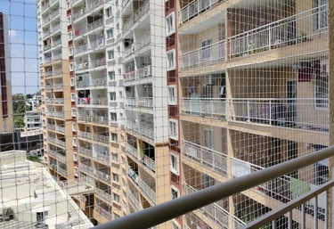 Wide shot of a high-rise building in Pallavaram with safety nets installed on multiple balconies.