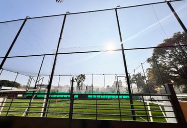 Close-up of hands securing a tightly woven net on a metal frame for a sports court.