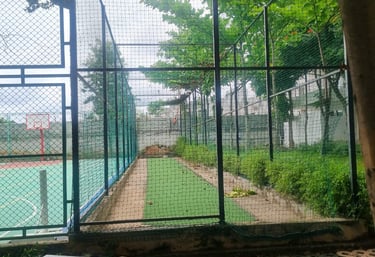 A technician carefully installing a cricket net on a sunny Chennai playground.