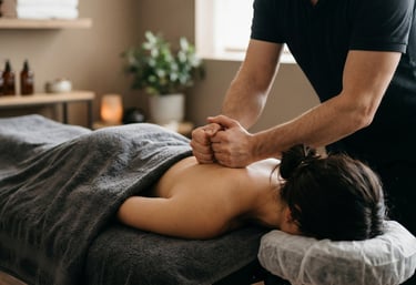 Male therapist applying deep tissue massage pressure to a female client's upper back.