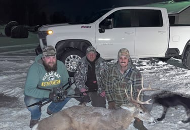 Three hunters posing with a harvested whitetail buck and thermal drone in the snow.