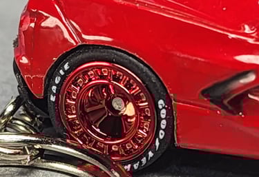 Close-up of a red die-cast toy car with metallic red rims and Goodyear Eagle branded tires.