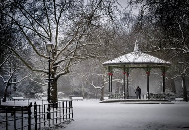 A scenic snowy park landscape featuring a traditional Victorian bandstand and bare winter trees.