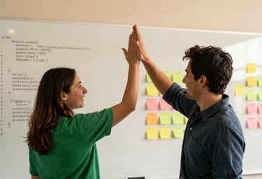 An action shot of two people in a North American tech hub high-fiving in front of a whiteboard filled with code and colorful sticky notes. The lighting is warm and community-focused, with Vibrant Green accents.