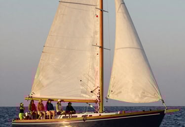 A moody landscape photograph of a dark charcoal lake at twilight, with deep slate mountains in the distance and a pale grey mist hovering over the water.