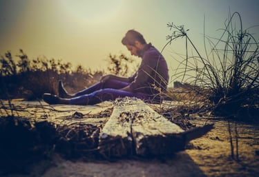 homme, assis dans la nature, en prise avec un mal-être
