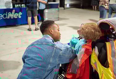 Photo of a person in an automated wheelchair speaking with someone hovering near them.