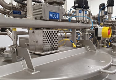 Industrial stainless steel chemical mixing tank with automated valves and pneumatic actuators.