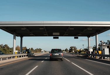 A vehicle passing through a sleek highway toll point with a blue sky background, emphasizing a seamless journey.