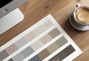 Wooden desk with a computer, a sheet with colour swatches, and a cup of cofee