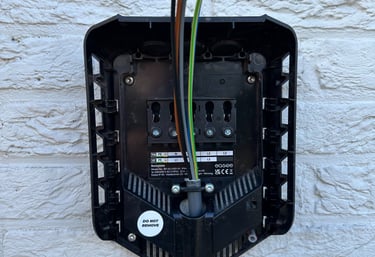 Internal wiring of an Easee electric vehicle charging station mounted on a white brick wall.