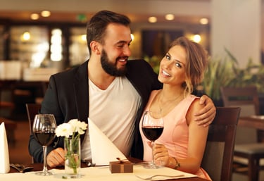 a sugar mommy and her sugar baby sitting at a table with wine glasses