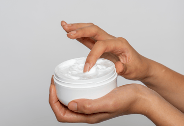 a person holding a jar of cream in their hands