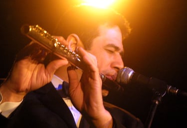 Maestro Bobby Ramirez in a tuxedo playing a flute