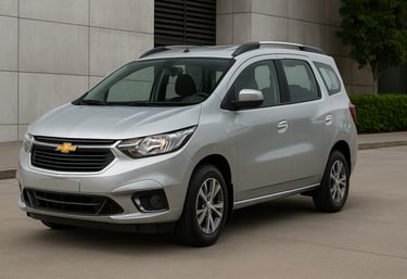 Chevrolet Spin prata vista de lado em ambiente externo, estacionada próxima a prédio moderno.