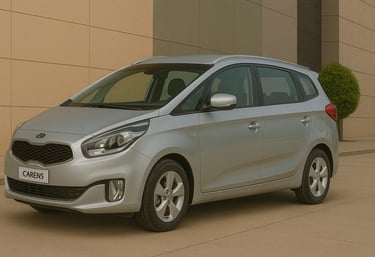 Kia Carens prata visto de lado em ambiente externo, estacionado diante de prédio moderno em tons beg