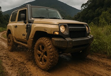 Troller 4x4 atravessando trilha de terra com lama, pneu sujo em destaque e vegetação lateral.