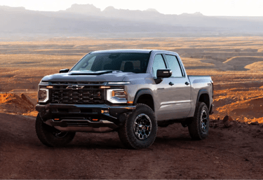 Chevrolet Silverado ZR2 prata em trilha off-road com paisagem desértica ao fundo.