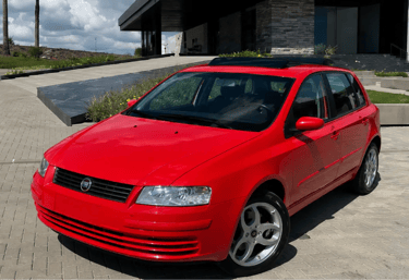 Fiat Stilo Schumacher vermelho estacionado em frente a uma casa moderna