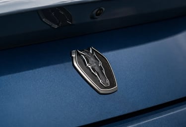 Emblema traseiro do Ford Mustang em close com acabamento azul metálico