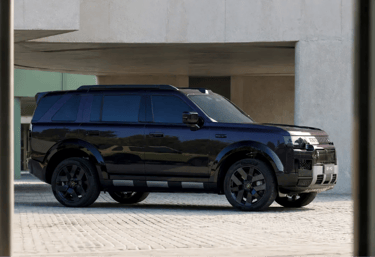 Freelander 8 preto estacionado em frente a edifício moderno com design robusto