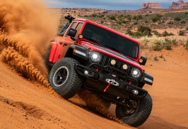 Jeep Wrangler vermelho acelerando em duna com visual off-road extremo.