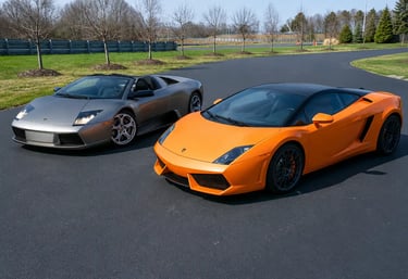 Lamborghini Murciélago prata e Gallardo laranja lado a lado em pista asfaltada.