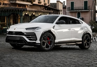 Lamborghini Urus branca estacionada em rua europeia de paralelepípedos.