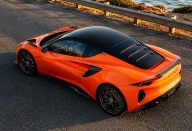 Lotus Emira 420 Sport laranja visto de cima em estrada costeira.