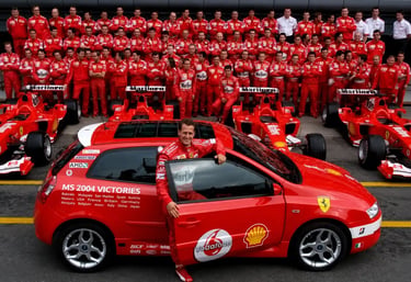 Michael Schumacher com equipe Ferrari, carros de Fórmula 1 e Stilo vermelho em 2004