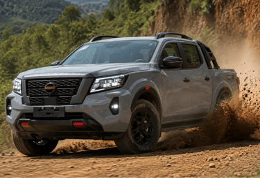 Nissan Frontier PRO-4X em movimento levantando terra em estrada rural