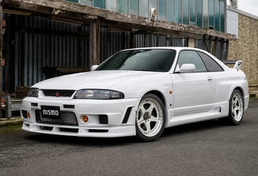 Nissan Skyline GT-R R33 Nismo 400R branco estacionado em cenário industrial