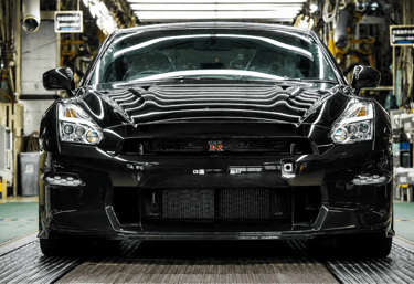 Novo Nissan GT-R preto com visual esportivo em fábrica iluminada.