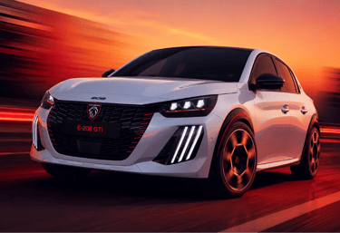 Peugeot E-208 GTi branco acelera em pista com visual esportivo e iluminação ao entardecer