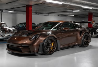 Porsche 911 GT3 RS marrom exclusivo em garagem com carros clássicos ao fundo