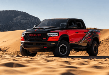 Picape Ram 1500 TRX vermelha estacionada em dunas no deserto com visual off-road agressivo e céu lim