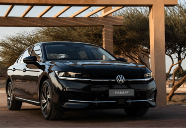 Volkswagen Passat Sedan preto em estrada desértica ao entardecer.