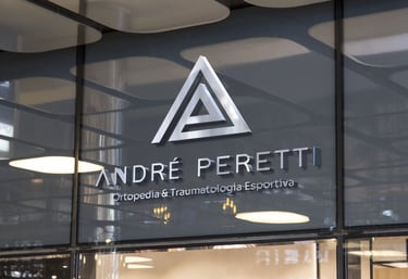 Fachada com logotipo metálico, triângulos e nome “André Peretti” sobre especialidade ortopédica.