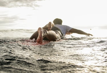 ucup laying on longboard surfboard in ocean