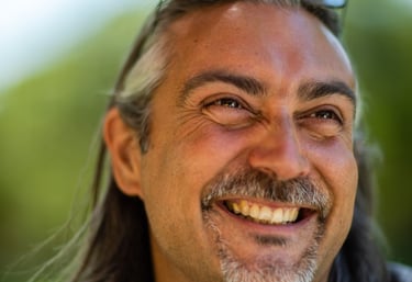 a man smiling with long hair and sunglasses on his head
