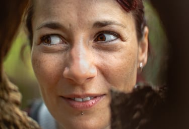 a woman smiling though a tree hole in the woods