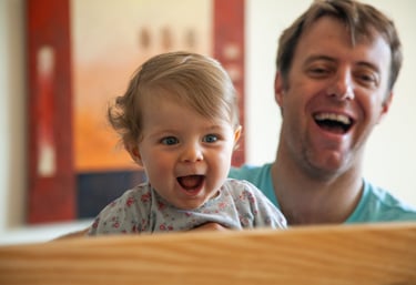a man and a baby are smiling and laughing in a mirror